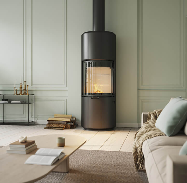 Großer schwarzer Holzofen Scan 87 Floor im grünen Zimmer mit hellbraunem Sofa und hellem Eichentisch