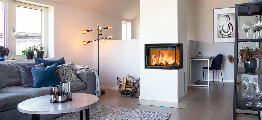 Kamineinsatz mit Glas auf zwei Seiten Scan 5003 in einem weißen modernen Wohnzimmer mit grauem Sofa und schwarzen Möbeln