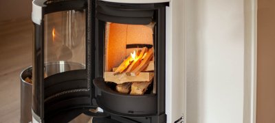 Weißer Kaminofen Scan 83-2 mit offener Tür und angezündetem Feuer