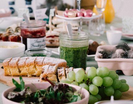 Ostern Dekorierter Tisch mit rosa Schalen und Buffet mit Brot, Weintrauben, Pesto und vielem mehr