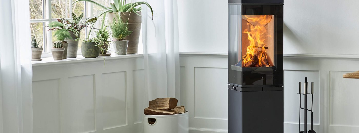 Top bild Wärmespeicherung. Ein schwarzer Kamin steht neben einer weißen Wand.