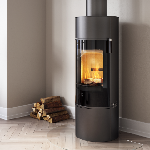 Schwarzer Stahlkamin mit schwarzer Glastür Scan 84 in einem Wohnzimmer mit braunem Sofa und hellgrauem Stuhl